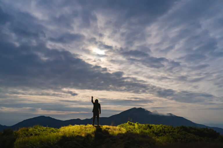 The man standing on a mountain on the sunny background